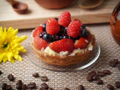 A closeup shot of a cake with strawberries and blueberries on a small plate